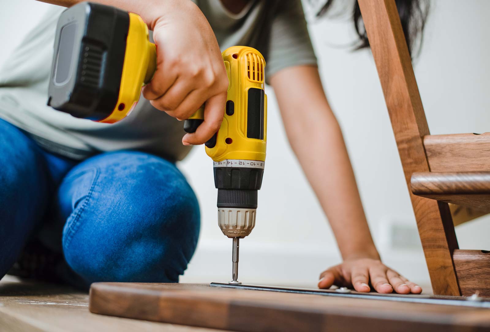 Image of a woman using a drill to assemble furniture